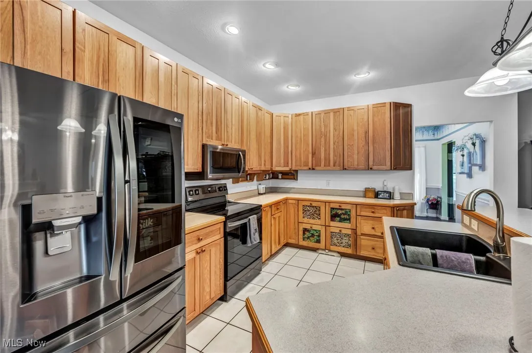 Kitchen with stainless steel appliances, light tile patterned flooring, light countertops, pendant lighting, and recessed lighting