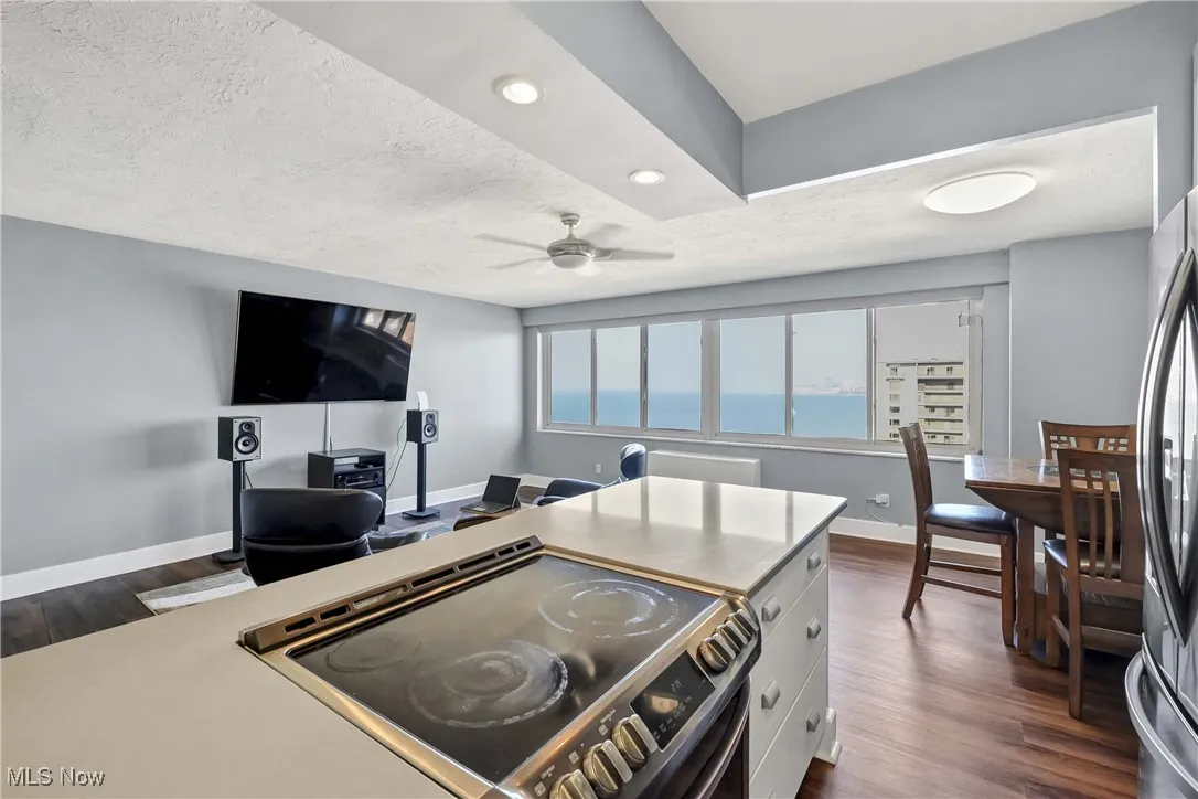 Kitchen with electric stove, dark wood-style floors, a textured ceiling, ceiling fan, and stainless steel refrigerator