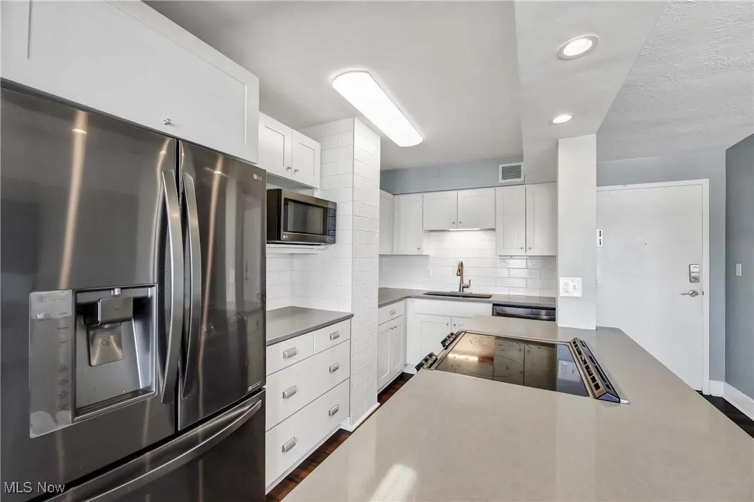 Kitchen with appliances with stainless steel finishes, white cabinets, recessed lighting, and decorative backsplash