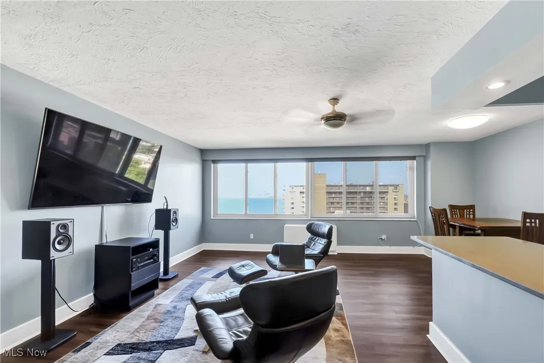 Living area featuring dark wood finished floors, a ceiling fan, and a textured ceiling