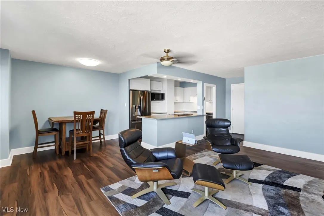 Living area featuring a ceiling fan, dark wood-style flooring, and a textured ceiling
