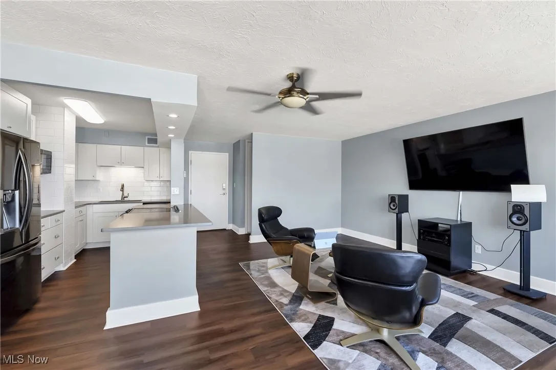 Living area with dark wood-style floors, a ceiling fan, a textured ceiling, and recessed lighting