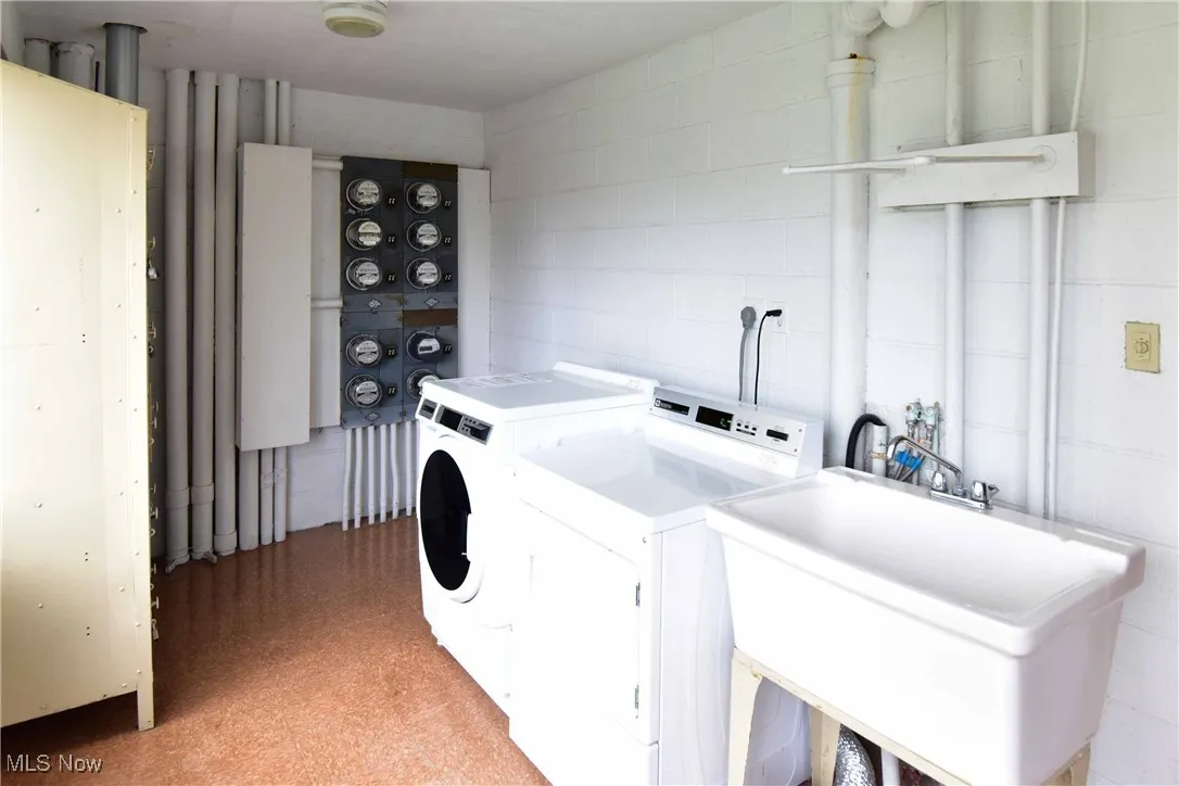 Washroom featuring washing machine and dryer and concrete block wall