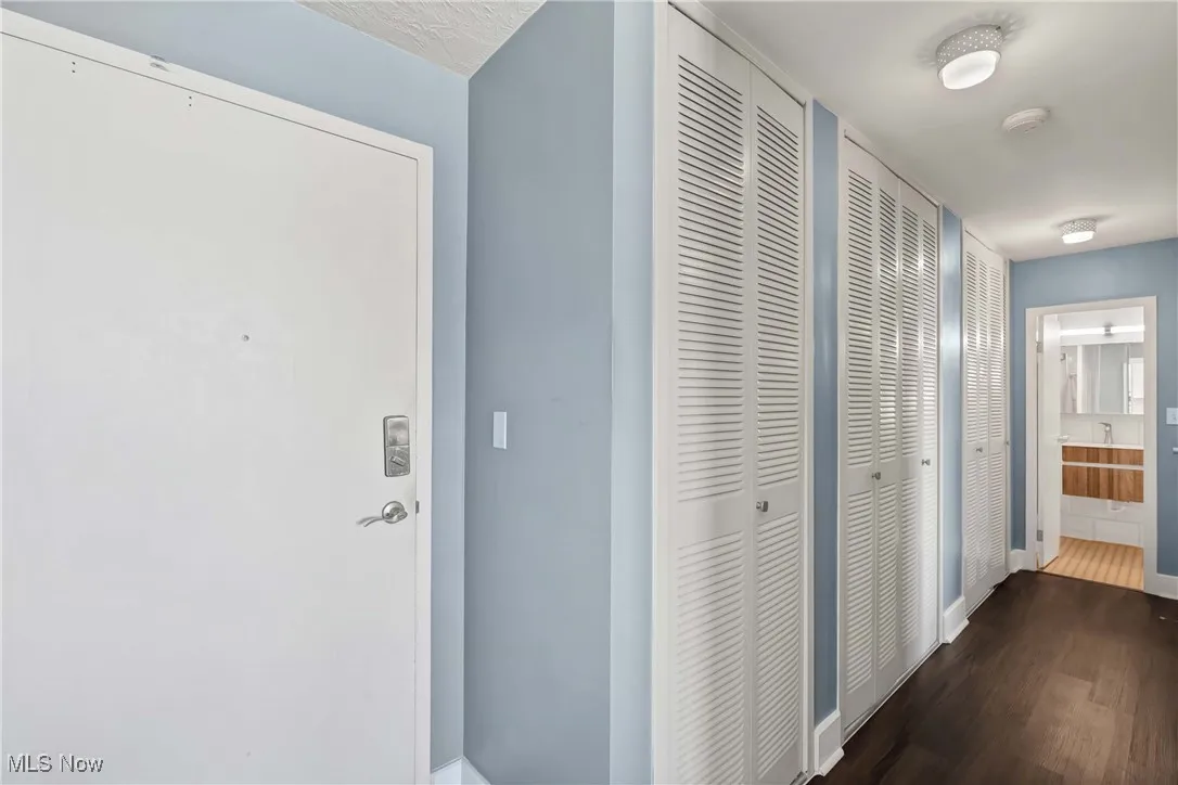 Corridor with dark wood-type flooring and baseboards
