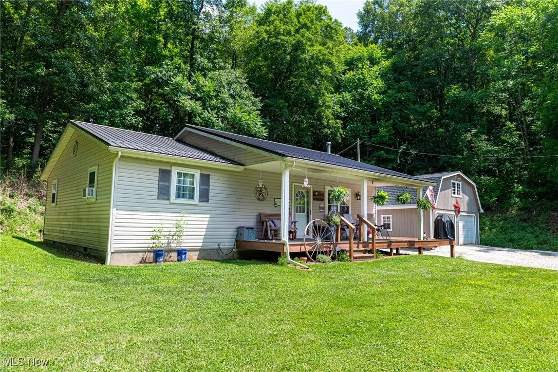 View of front facade featuring an outbuilding, a metal roof, crawl space, a porch, and a front lawn