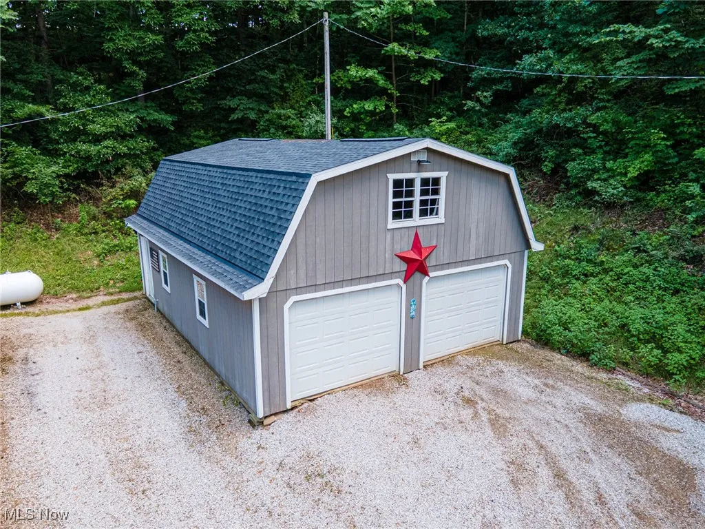 Garage featuring a detached garage, driveway, and a wooded view