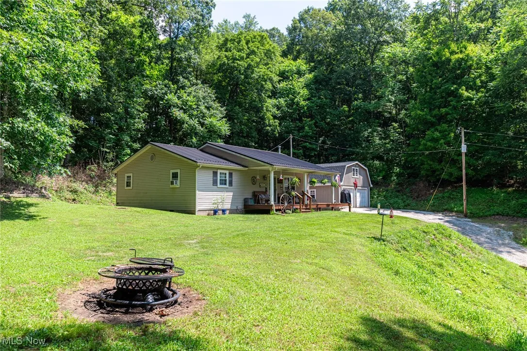 View of front of property featuring an outdoor fire pit, an outdoor structure, a front yard, a porch, and driveway
