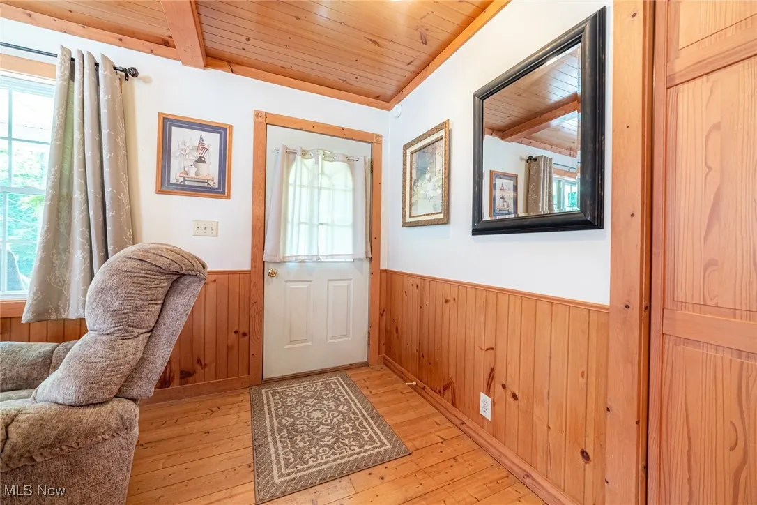 Foyer with a wainscoted wall, plenty of natural light, wood ceiling, light wood-style floors, and wood walls