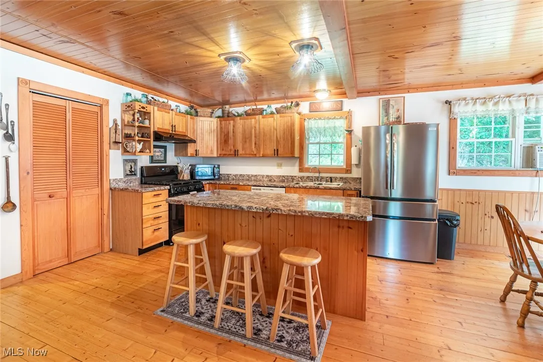 Kitchen featuring appliances with stainless steel finishes, a kitchen island, wooden ceiling, light wood finished floors, and plenty of natural light