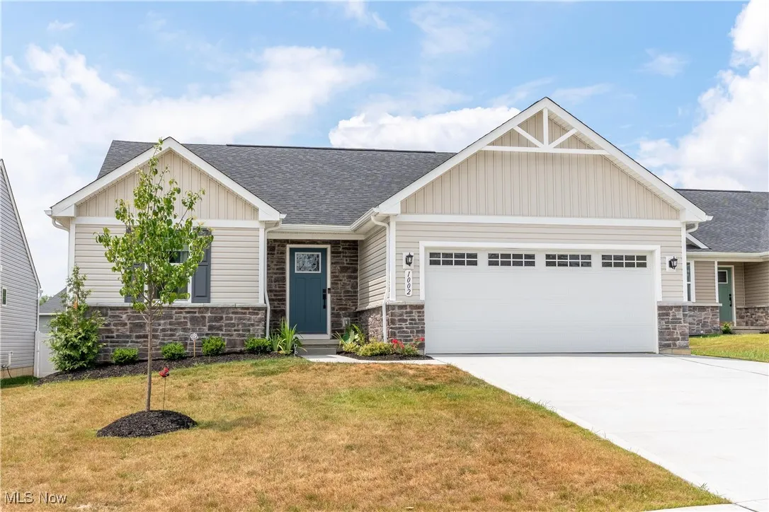 Craftsman inspired home with stone siding, an attached garage, board and batten siding, and a front yard