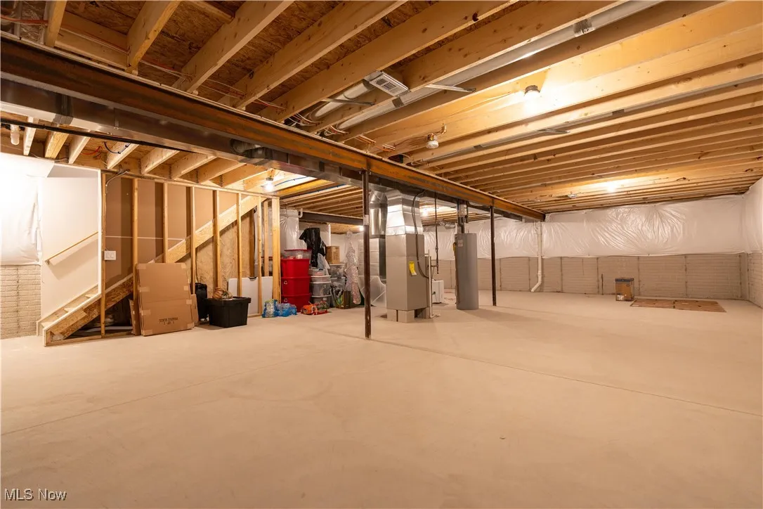 Unfinished below grade area featuring heating unit and water heater