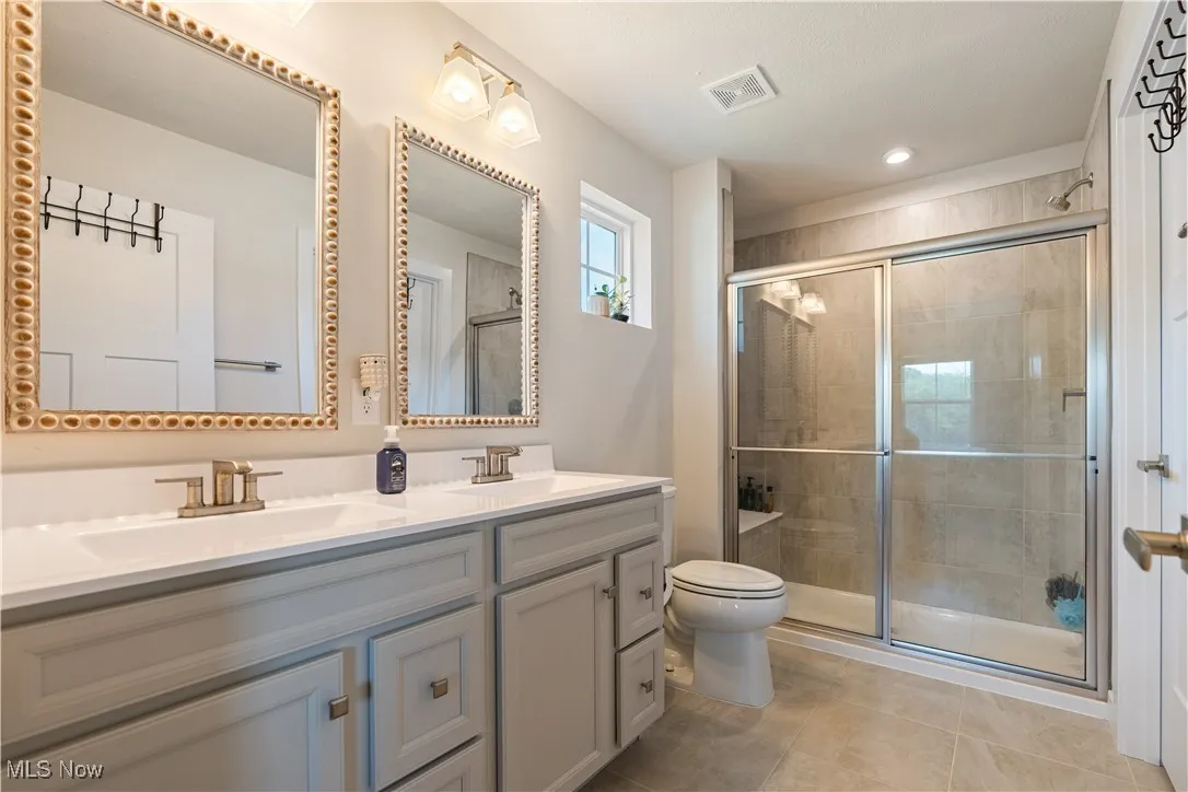 Bathroom with double vanity, tile patterned floors, a stall shower, and recessed lighting