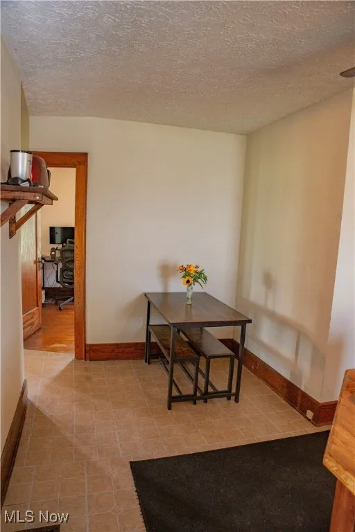 Tiled dining area with a textured ceiling and baseboards