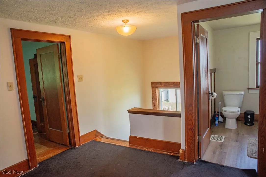 Carpeted empty room with a textured ceiling and wood finished floors