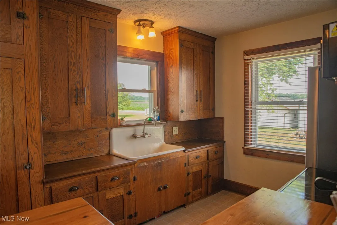 Kitchen with brown cabinetry, healthy amount of natural light, freestanding refrigerator, and a textured ceiling