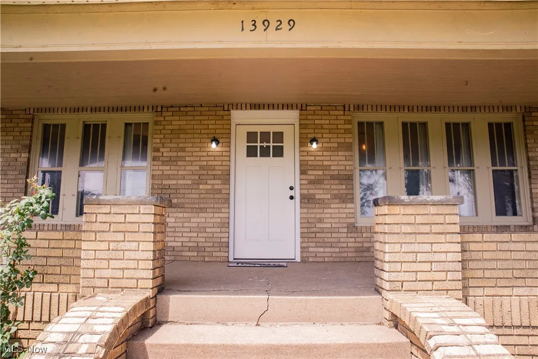 Doorway to property featuring covered porch and brick siding