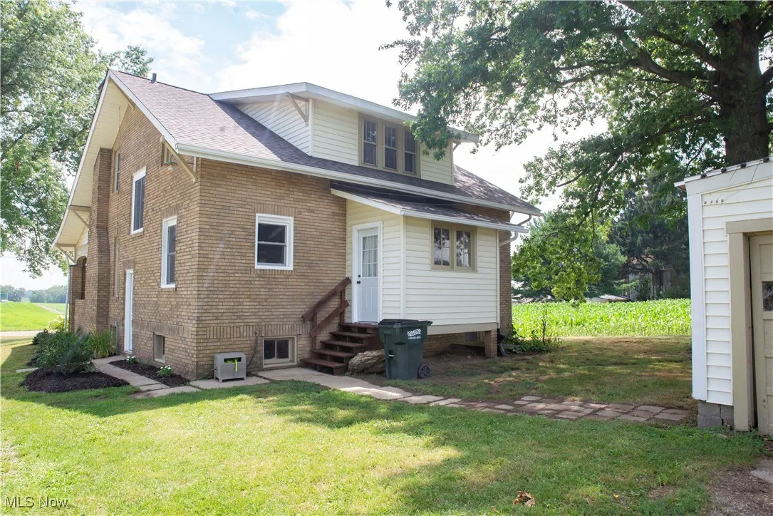 Rear view of house with entry steps, a yard, and a shingled roof