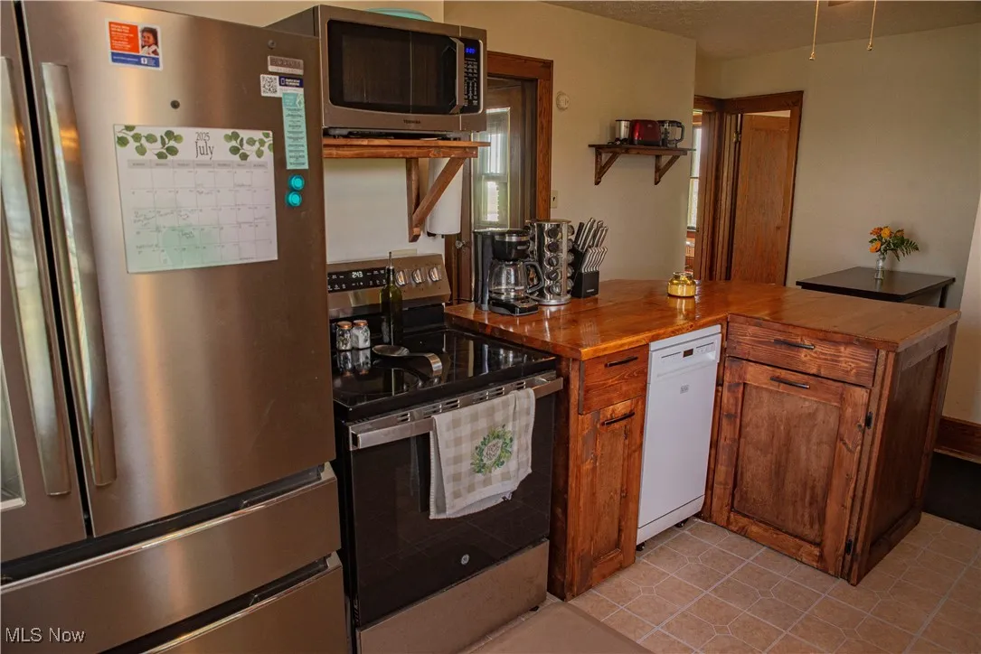 Kitchen featuring stainless steel appliances, brown cabinetry, and a peninsula