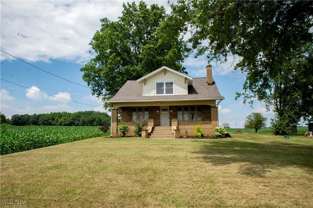 Bungalow-style home with brick siding, a chimney, a front lawn, and roof with shingles