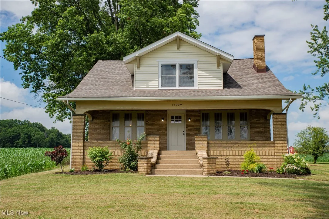 Bungalow with a front yard, brick siding, and a chimney