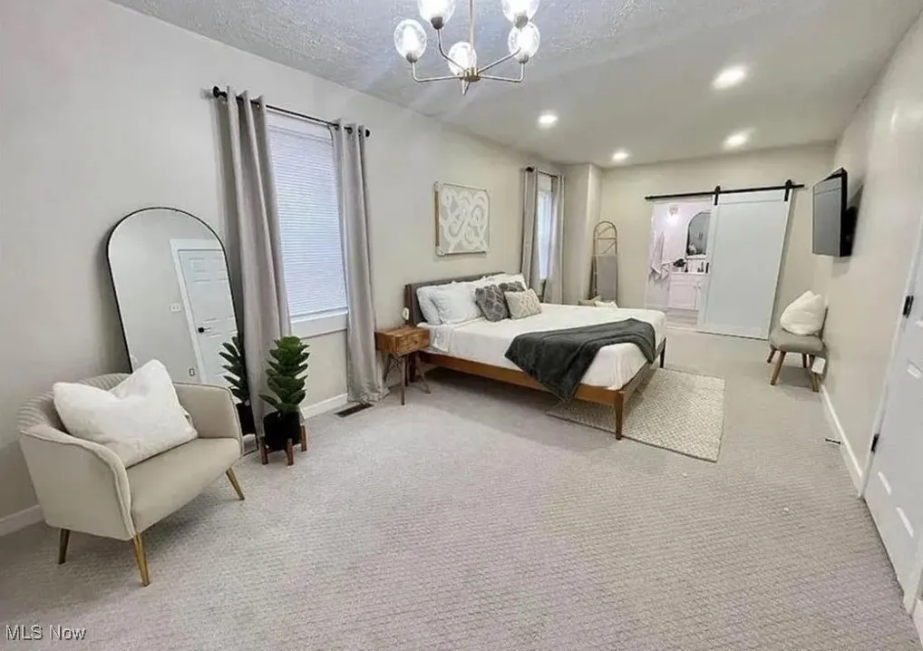 Carpeted bedroom with a chandelier, a barn door, multiple windows, recessed lighting, and a textured ceiling