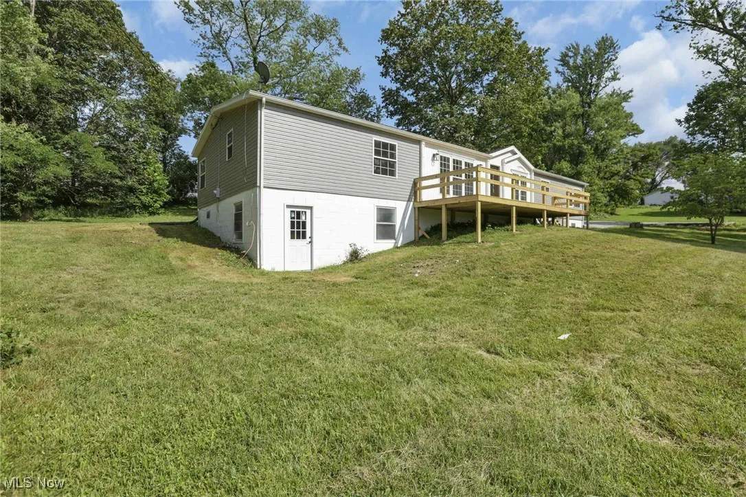 Rear view of house featuring a deck and a yard