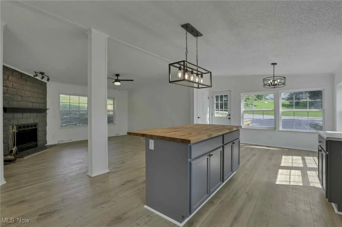 Kitchen with butcher block countertops, open floor plan, gray cabinetry, light wood-type flooring, and a textured ceiling