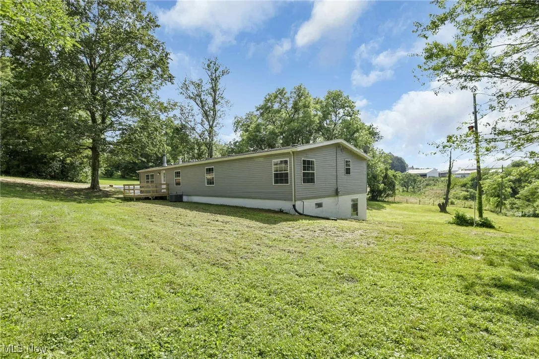 Back of house with a lawn and a wooden deck