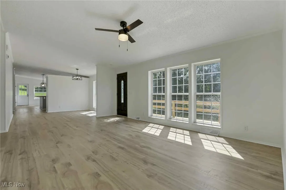 Unfurnished living room with wood finished floors, ceiling fan, and a chandelier