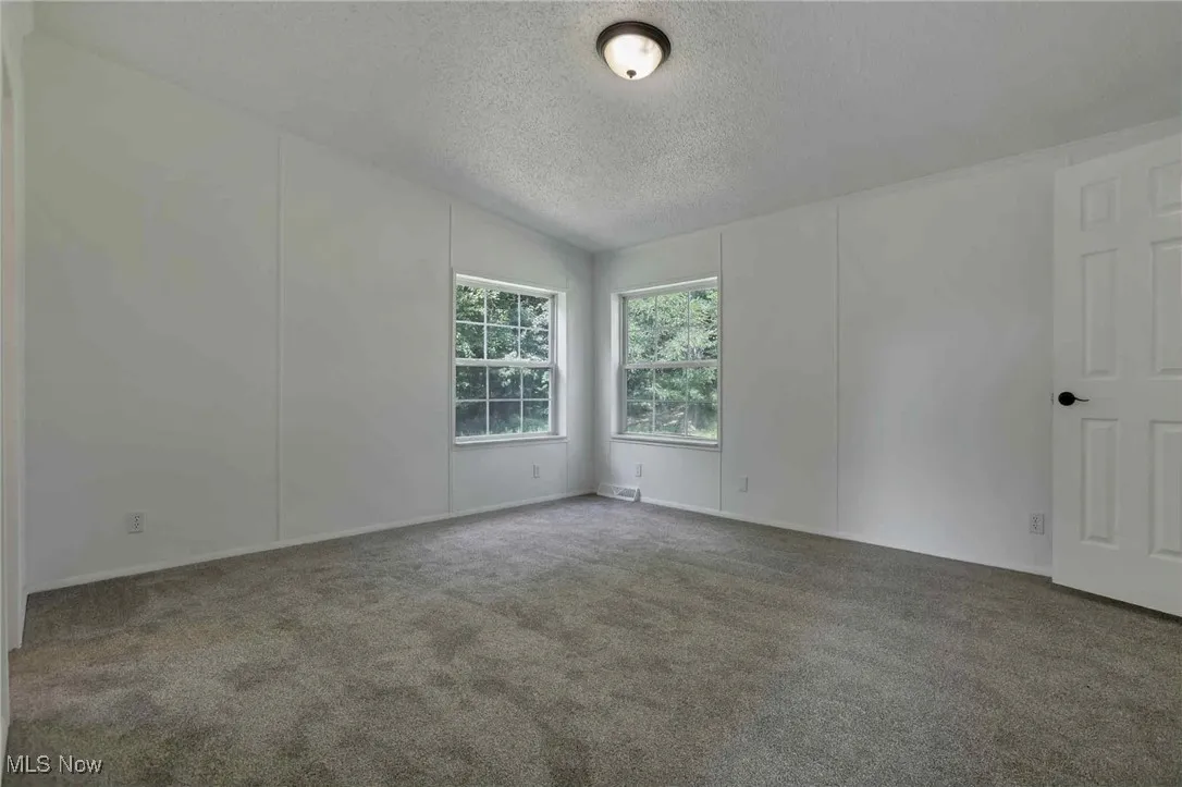 Spare room with carpet floors, a textured ceiling, and vaulted ceiling