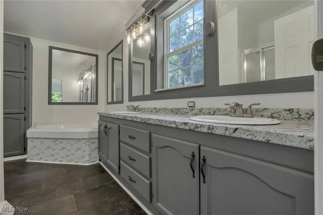 Bathroom featuring double vanity, a garden tub, and an enclosed shower