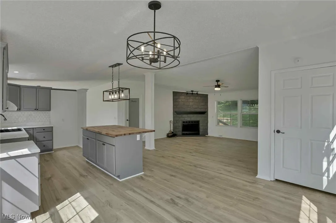 Kitchen featuring butcher block counters, gray cabinets, a chandelier, ceiling fan, and a textured ceiling