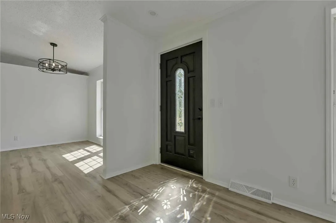 Entryway with a chandelier, wood finished floors, and a textured ceiling