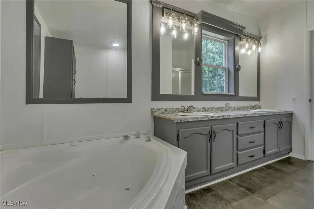 Bathroom with a whirlpool tub, double vanity, and ornamental molding