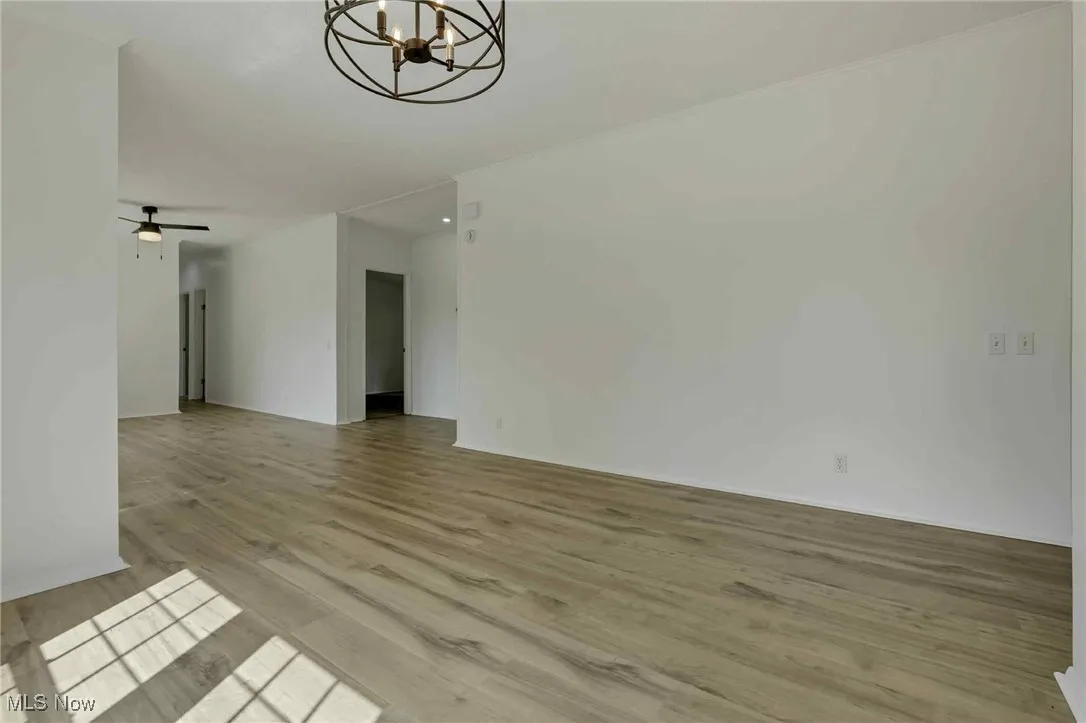 Spare room featuring a chandelier, wood finished floors, and ceiling fan