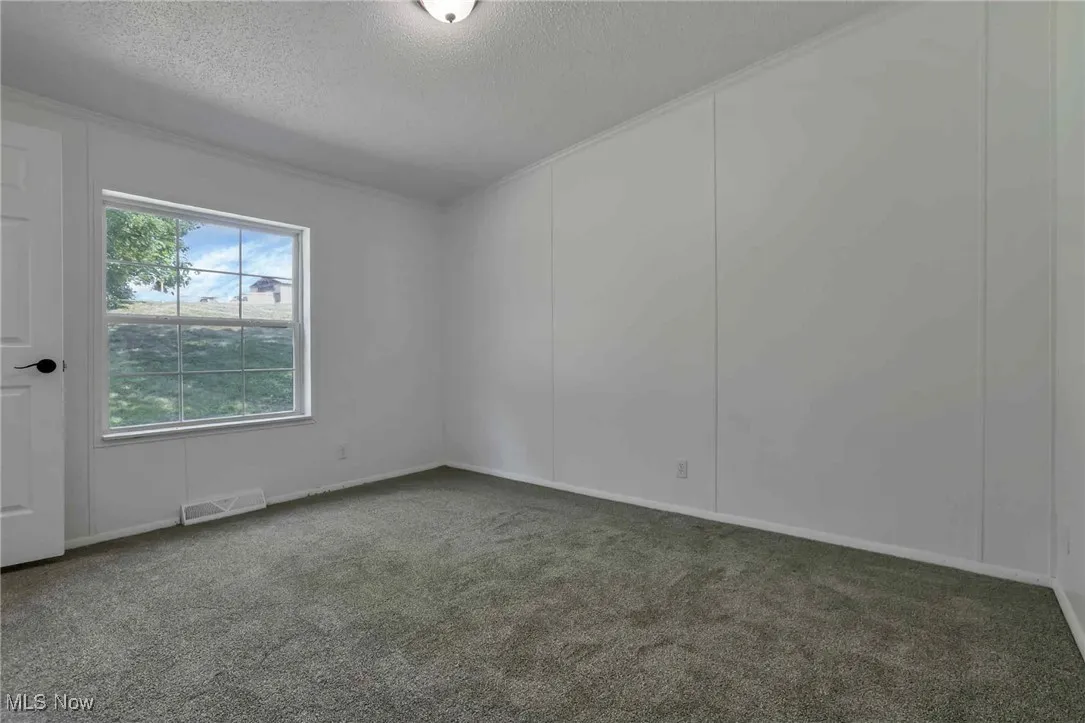 Carpeted empty room featuring a textured ceiling