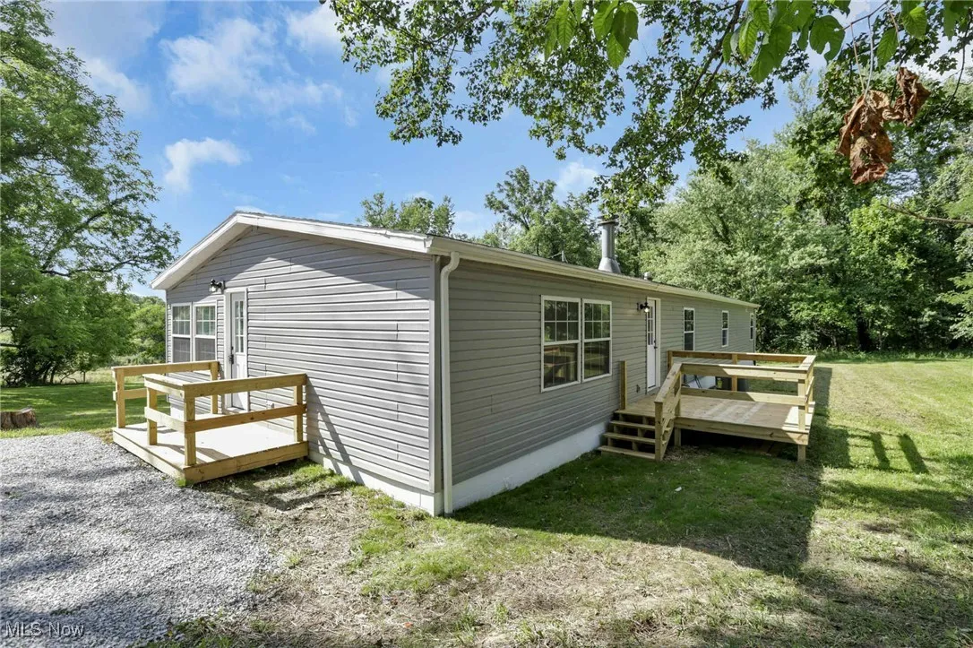 View of side of property with a wooden deck and a lawn
