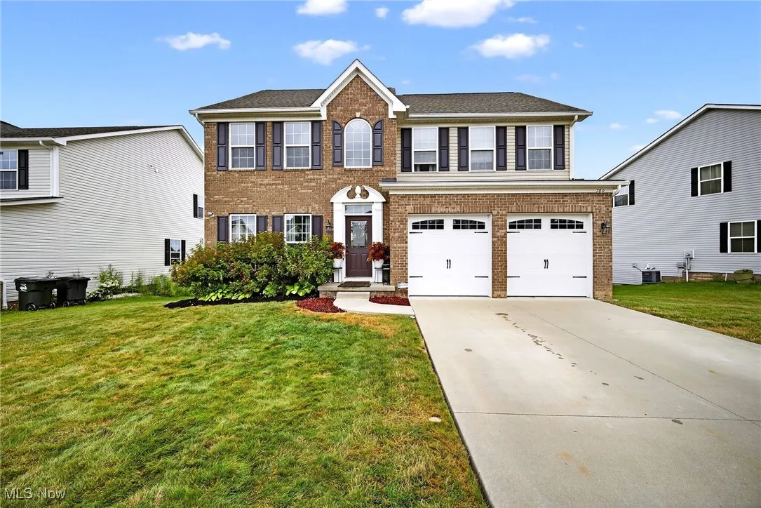 Colonial inspired home with brick siding, a garage, and a front lawn