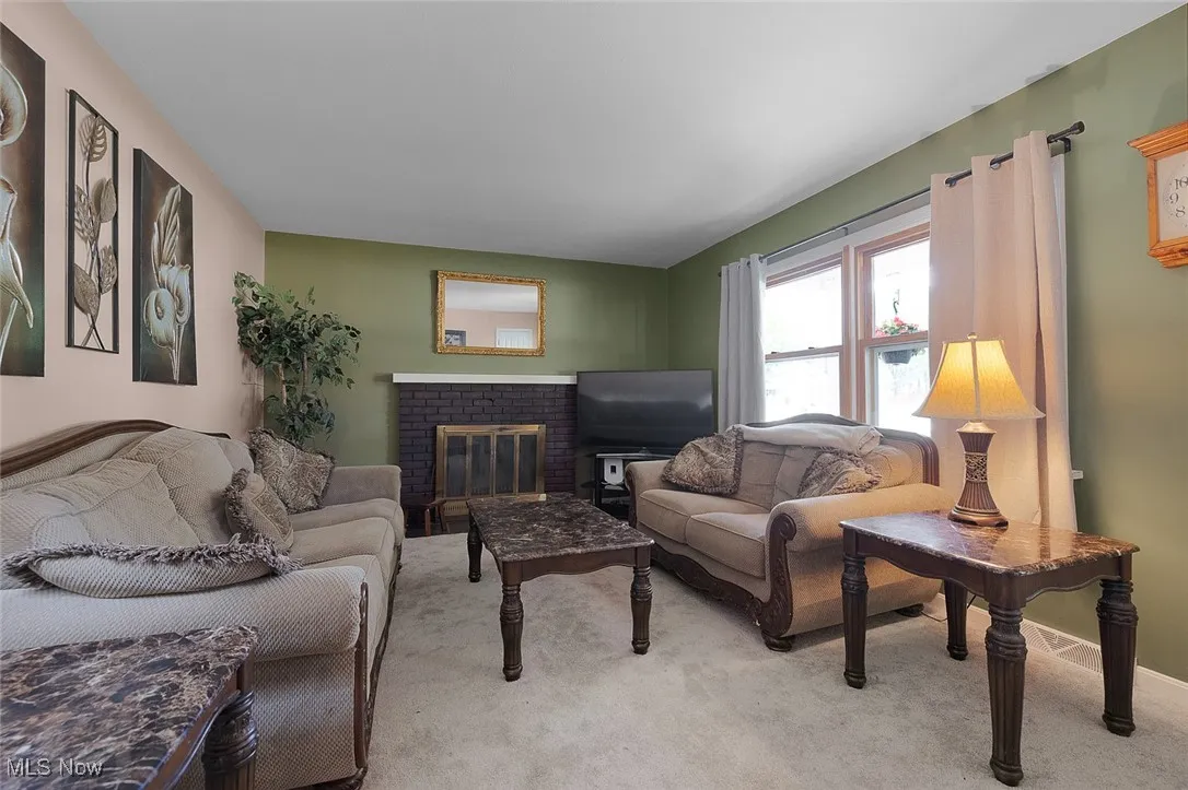 Carpeted living room with a fireplace and baseboards