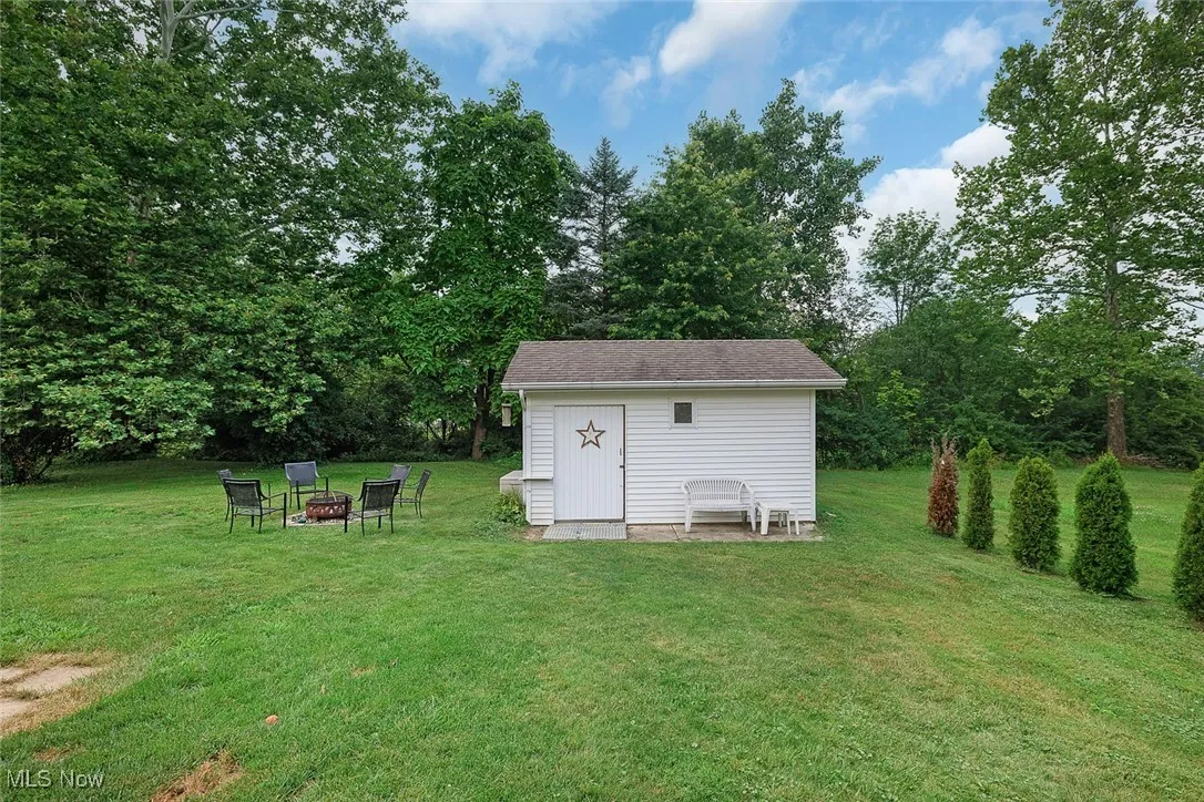View of green lawn featuring an outdoor fire pit and a shed