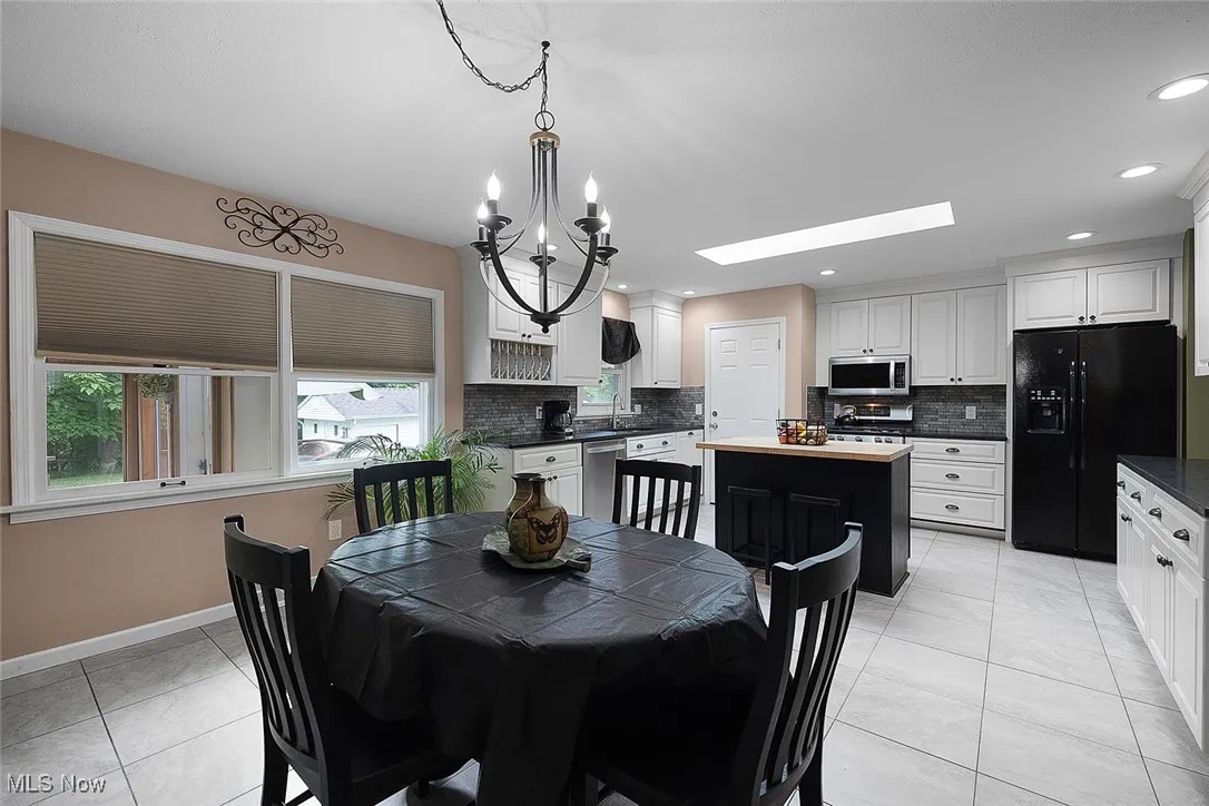 Dining room with a chandelier, a skylight, recessed lighting, and light tile patterned flooring