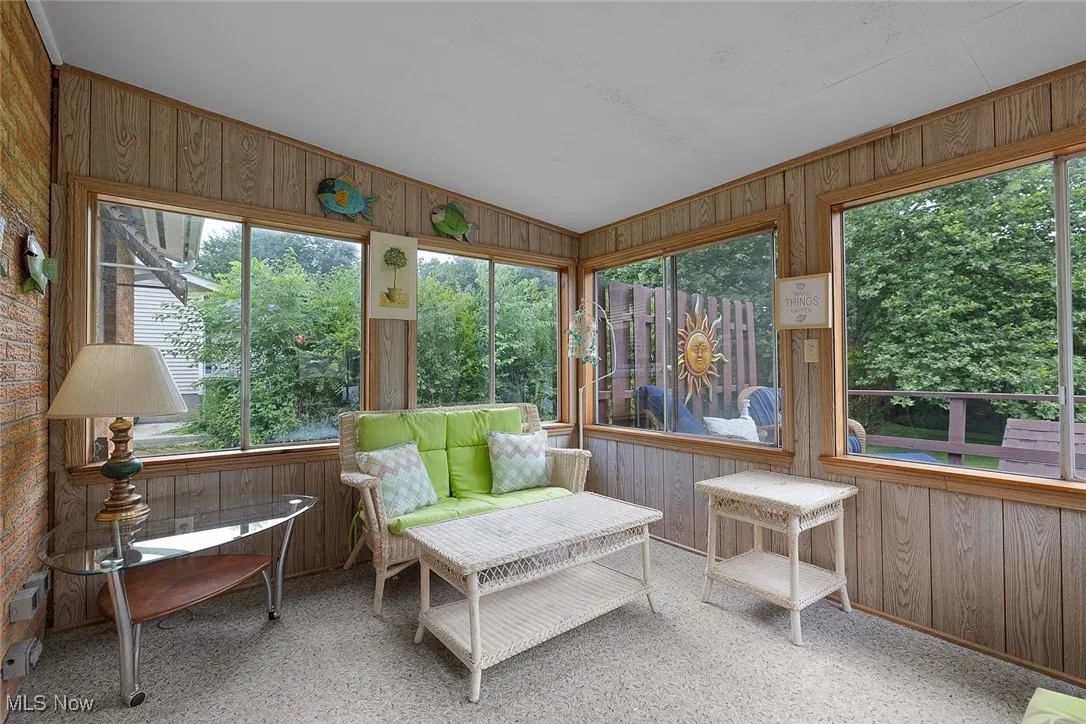 Sunroom / solarium featuring wood walls and vaulted ceiling