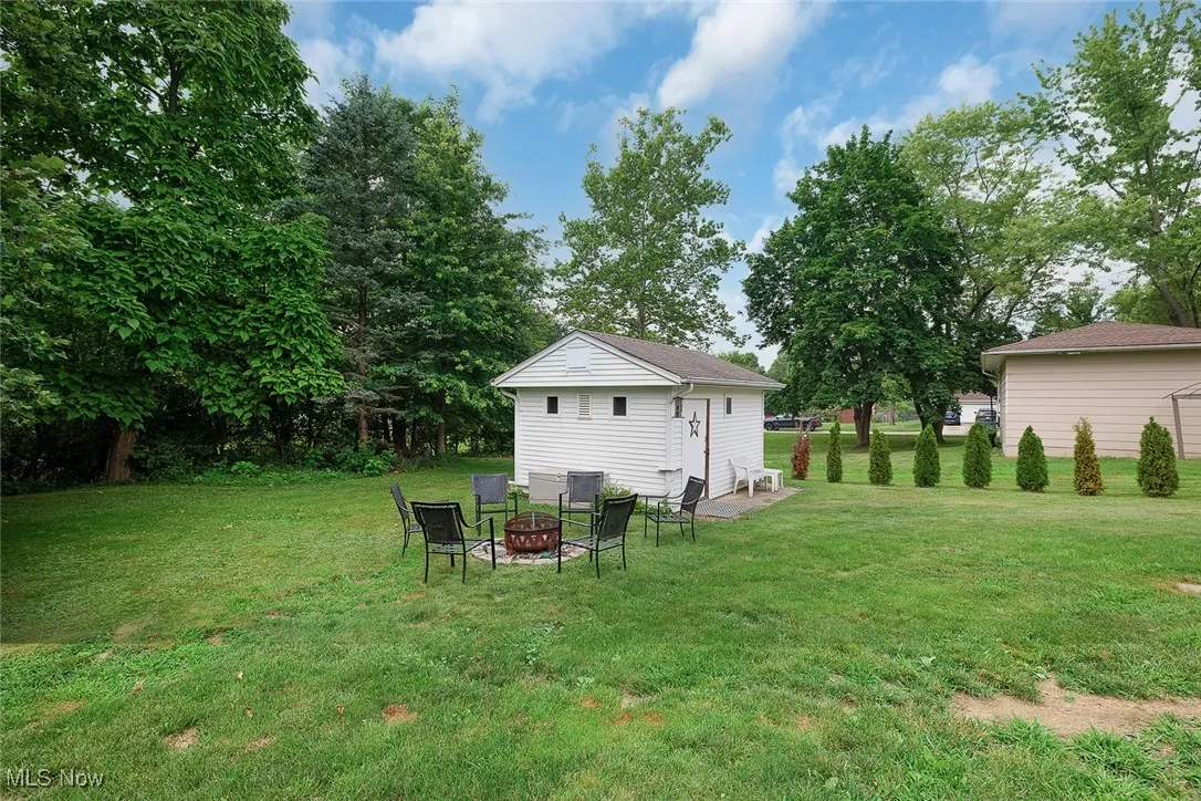 View of grassy yard featuring an outdoor fire pit