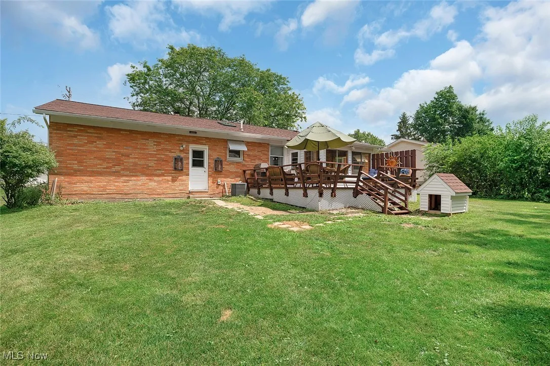 Rear view of property featuring a wooden deck, a shed, brick siding, and a yard