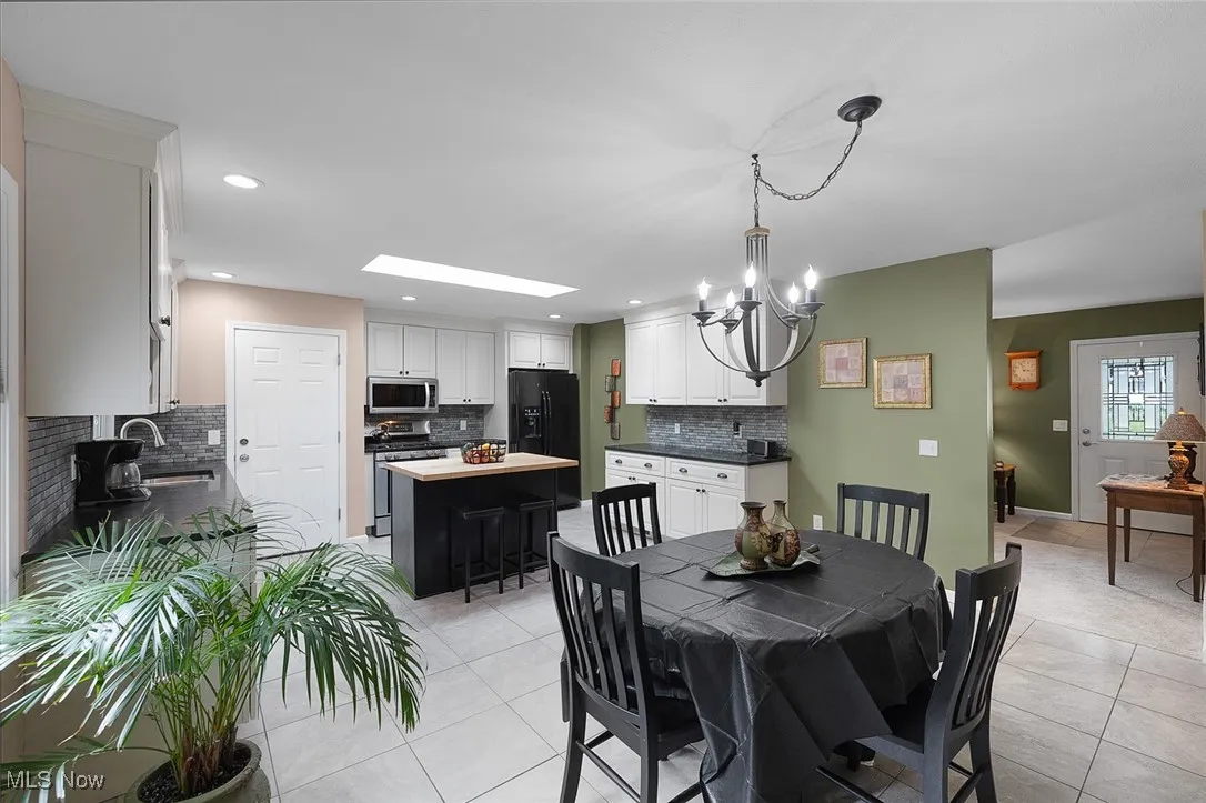 Dining room with light tile patterned floors, a chandelier, recessed lighting, and a skylight