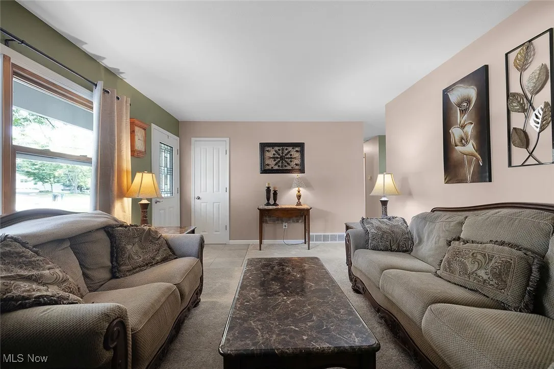 Living area featuring light colored carpet and baseboards