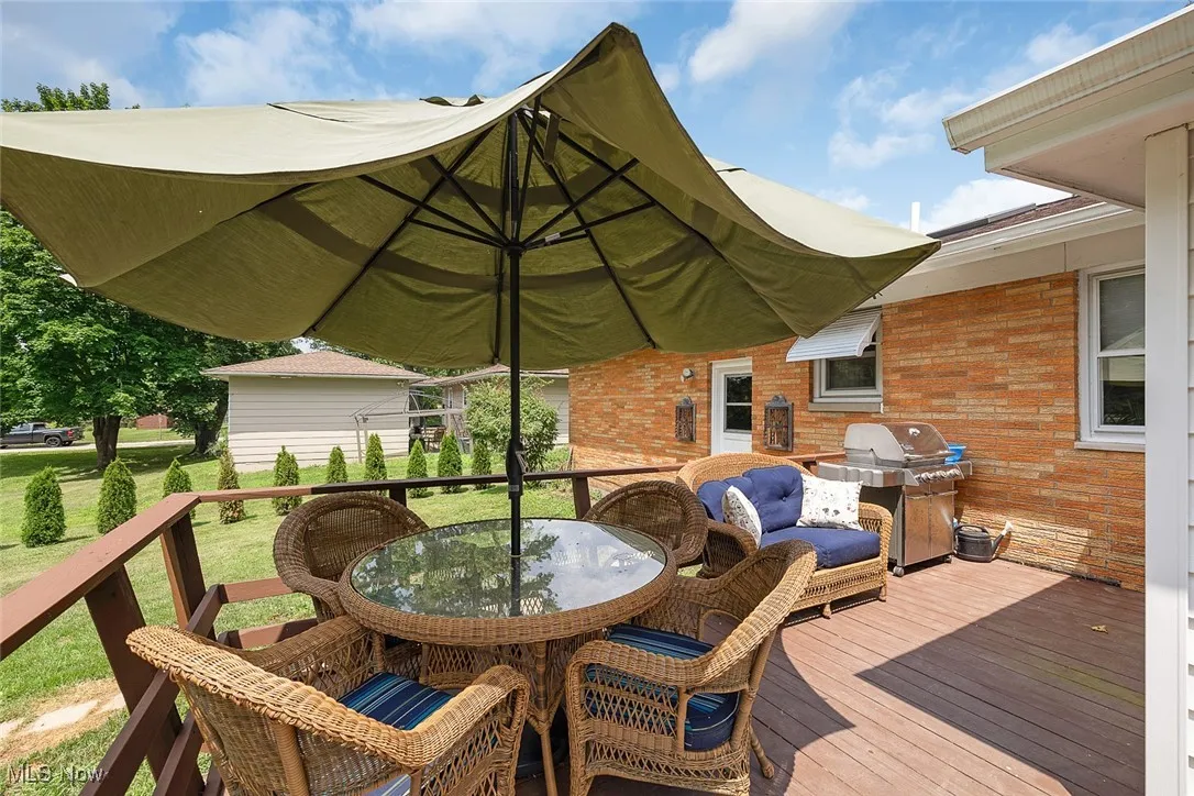 Wooden terrace with outdoor dining area, area for grilling, and a yard