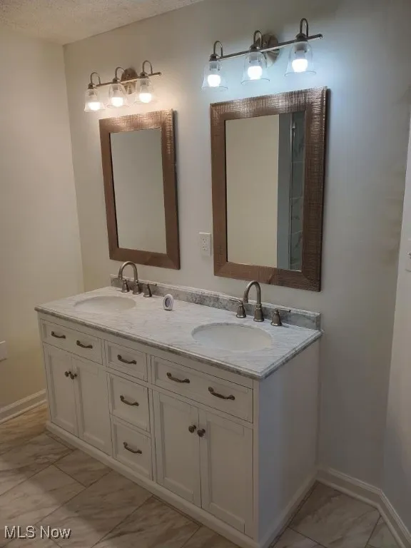 Bathroom featuring double vanity and marble finish flooring