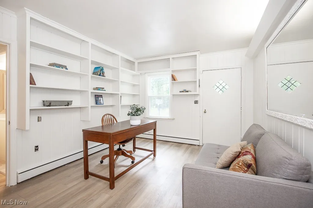 Office area with light wood-type flooring, a baseboard radiator, and built in shelves