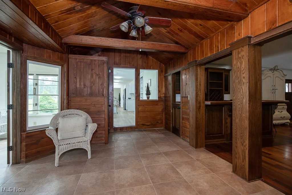 Sitting room with wooden ceiling, wooden walls, and a ceiling fan